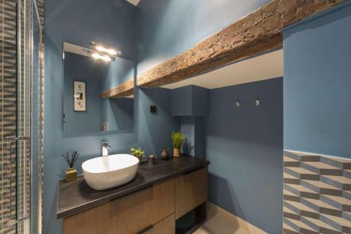 巴黎的住宿－Contrevents，浴室设有白色水槽和蓝色的墙壁。