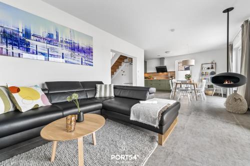 a living room with a black leather couch and a table at Ferienhaus Villa Dein Zuhause am Meer in Büsum