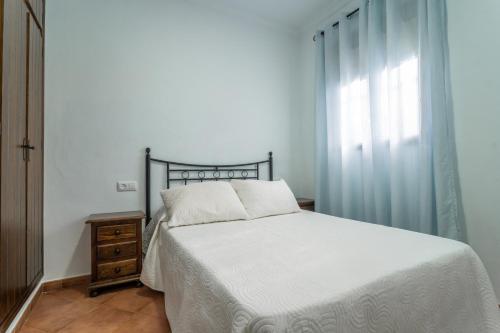 een slaapkamer met een wit bed en een raam bij EntreCalas 1 Chalet con jacuzzi en Conil, Roche viejo, cala del aceite in Conil de la Frontera
