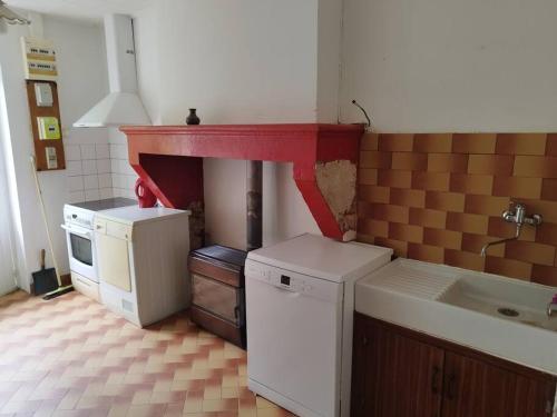 een keuken met een fornuis en een rode mantel bij Bienvenue en sud gironde in Villandraut