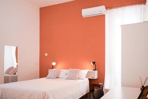 a bedroom with a white bed and an orange wall at From Home to Vesuvius - Close to Pompeii, Herculaneum, and the Heart of Naples in Torre del Greco