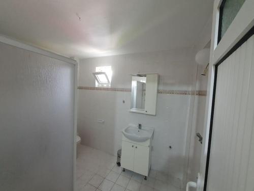 a white bathroom with a toilet and a sink at A Vacation House 60 m. To Seashore in Kusadası