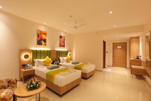 Habitación de hotel con 2 camas y sofá en THE GRAND AMBASSADOR HOTEL, en Kottayam