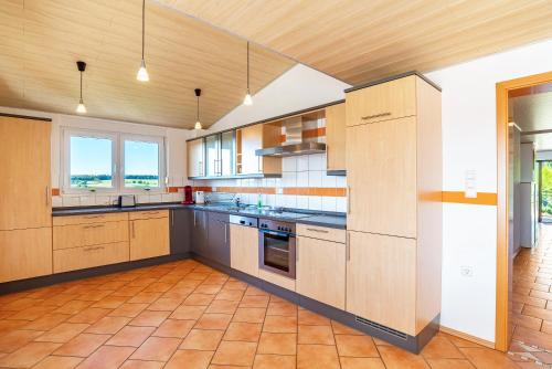 a large kitchen with wooden cabinets and appliances at Hügelblick Oase in Kraichtal