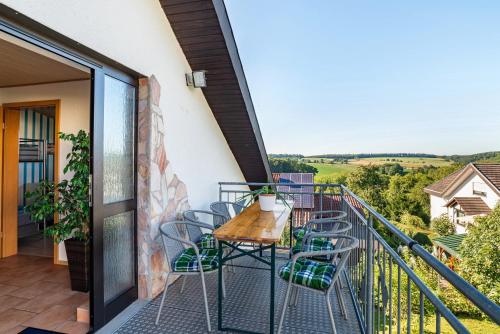a balcony with a wooden table and chairs at Hügelblick Oase in Kraichtal