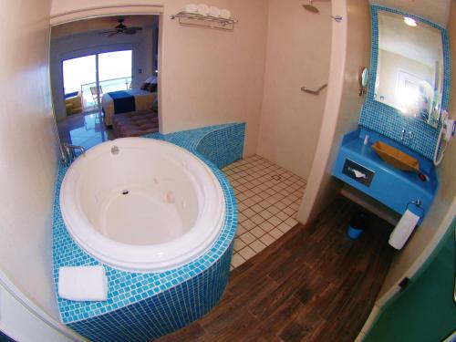a bathroom with a tub with a mirror and a sink at Mar Celeste in Manzanillo