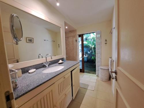 y baño con lavabo y espejo. en Serenity - Cheerful 2-Bedrooms Beachfront Villa., en Trou d'Eau Douce