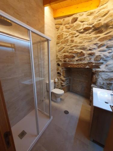 a bathroom with a shower and a toilet and a stone wall at Casa da Marquinhas - Turismo Rural in Lama de Ouriço