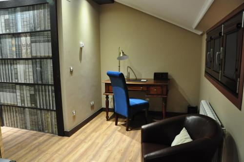 a room with a desk and a blue chair and a computer at Hotel Calzada in Arcos