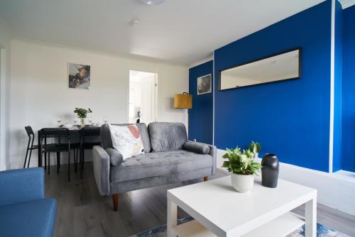 sala de estar con sofá y pared azul en Dunalastair Apartment en Glasgow