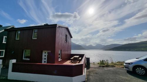 a house with a car parked next to a body of water at The Cozy red house with Amazing sea view in Morskranes