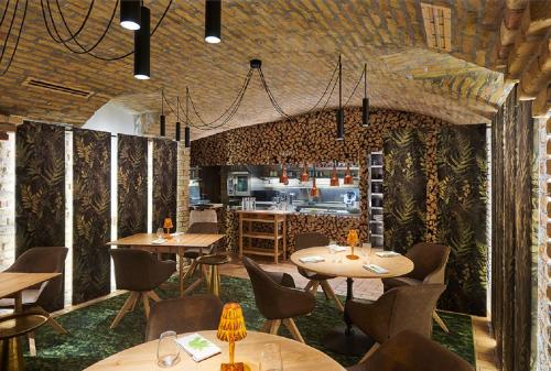 a restaurant with tables and chairs and a kitchen at Platan Udvarhaz in Tata