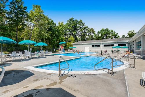 a large swimming pool with chairs and umbrellas at Sea Colony---1805 Doubles Court in Bethany Beach