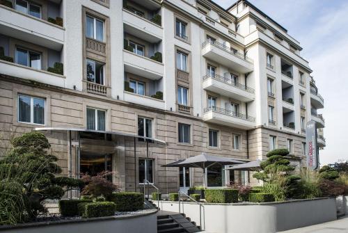 a large white building with an umbrella in front of it at Hotel Mon Repos in Geneva