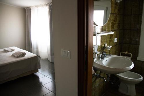 bagno con lavandino, letto e specchio di Hotel Arianna a Iseo