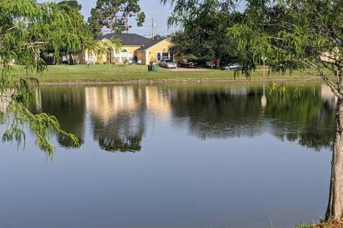 a lake with a tree and a house in the background at Port Saint Lucie A Little Piece Of Heaven- Peaceful Lake view Apartment- 1 min from I95 and Turnpike in Port Saint Lucie