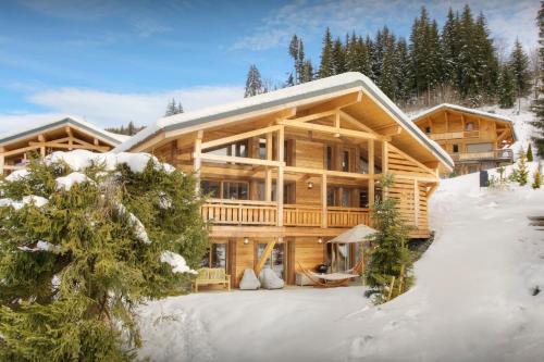 une grande cabane en rondins dans la neige avec des arbres dans l'établissement Chalet Behansa - OVO Network, aux Gets