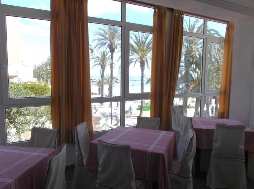 a dining room table with chairs and umbrellas at Hotel Lido in Santiago de la Ribera