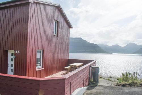a red building next to a body of water at The Cozy red house with Amazing sea view in Morskranes