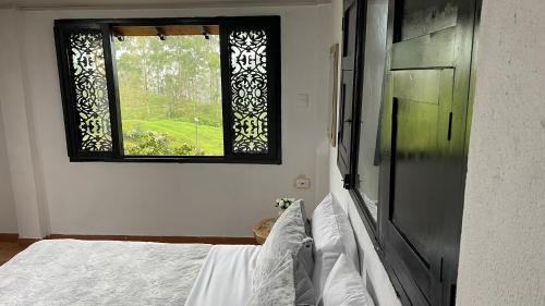 a bedroom with a bed and a window at Aguas Claras Luxury Hospedaje in Filandia