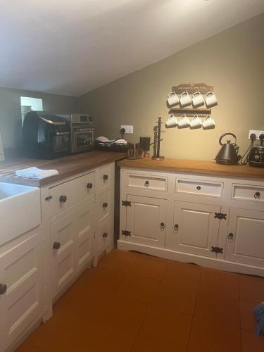 a kitchen with white cabinets and a counter top at Little half point in Welton