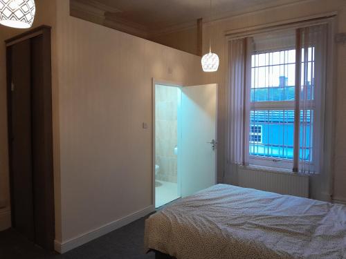 a bedroom with a bed and a large window at Falcon Villa in Grimsby