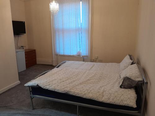 1 dormitorio con cama, ventana y TV en Falcon Villa en Grimsby