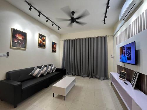 a living room with a black couch and a ceiling fan at MardOne’s Resthouse in Sandakan