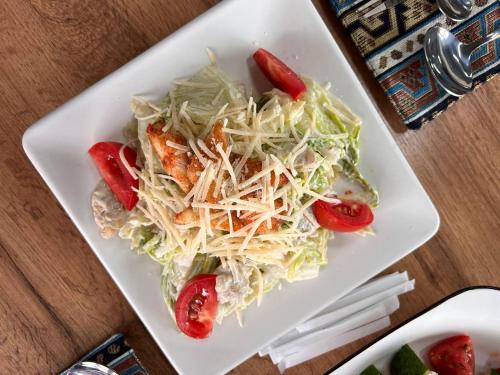 un plato blanco con una ensalada en una mesa en Royal Gate at Skazka Canyon, en Tong