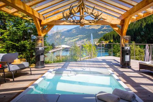 a swimming pool on a patio with a wooden roof at Chalet Ruisselet - OVO Network in Châtel