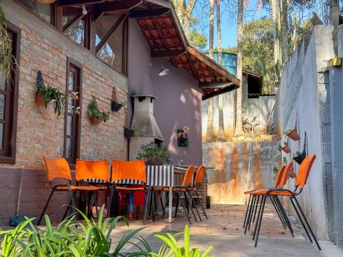an outdoor patio with orange chairs and a table at Cantareira - Deck House in Mairiporã