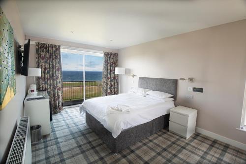 a bedroom with a bed and a large window at Poseidon Inn in Lossiemouth