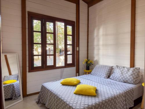 a bedroom with a bed with yellow pillows on it at Cantareira - Deck House in Mairiporã