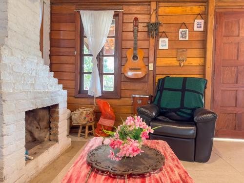 a living room with a leather chair and a fireplace at Cantareira - Deck House in Mairiporã