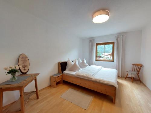 a bedroom with a bed and a table and a window at Mandla's Hoamat in Umhausen