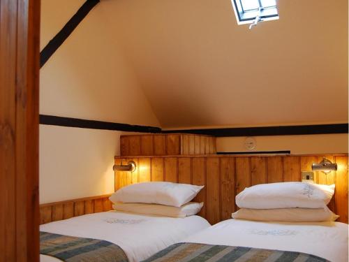 two beds in a bedroom with a roof at The Plume of Feathers in Farnham