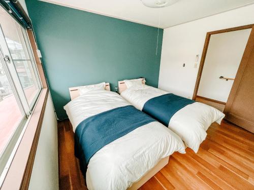 two beds in a room with a green wall at シテコベハウス in Yokosuka