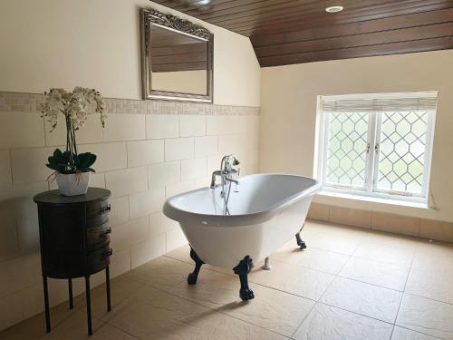 duża łazienka z wanną i oknem w obiekcie The Kingfisher w mieście Bedford
