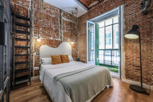 a bedroom with a bed and a brick wall at Apartamento centrico y comodo Preciados in Madrid