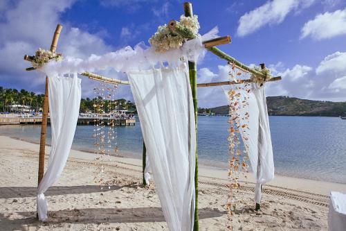 an altar on the beach with white curtains and flowers at St. James's Club Resort - All Inclusive in English Harbour Town