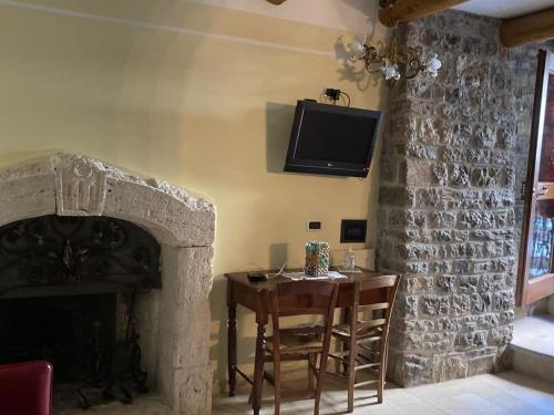 uma sala de estar com uma mesa e uma televisão na parede em La torre della manca suite em Sasso di Castalda
