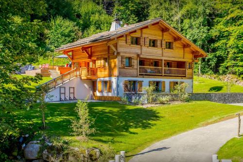 a large wooden house on a lush green yard at Chalet Riparian - OVO Network in La Clusaz
