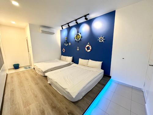 2 camas en una habitación con una pared azul en H&H 1 Guest House en Melaka