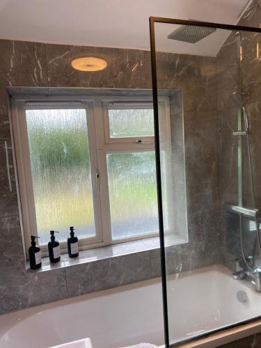 a bathroom with a bath tub and a window at Spacious family friendly 3 bedroom Home With Hot tub & 75tv in Potters Bar
