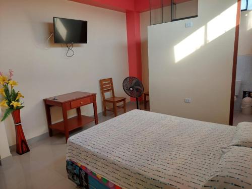 a bedroom with a bed and a table and a tv at HOTEL POSEIDON in Chiclayo