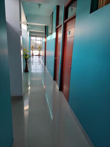 um corredor num edifício com paredes azuis e pisos brancos em HOTEL POSEIDON em Chiclayo