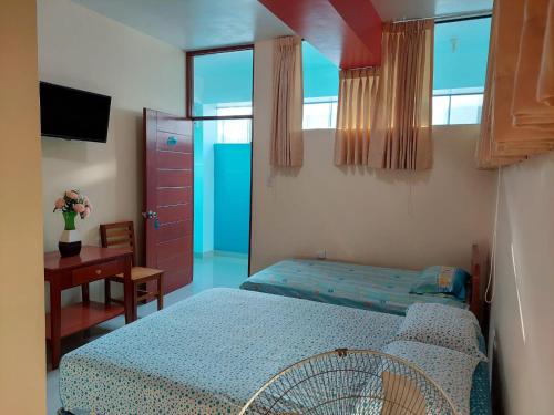 een slaapkamer met een bed, een bureau en een raam bij HOTEL POSEIDON in Chiclayo