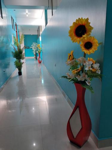 a red vase with a bouquet of flowers in a hallway at HOTEL POSEIDON in Chiclayo