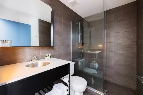 a bathroom with a sink and a toilet and a shower at Le Dauphin St-Hyacinthe in Saint-Hyacinthe
