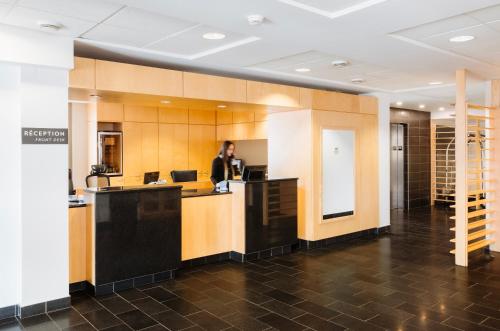 a man standing at a counter in an office lobby at Le Dauphin St-Hyacinthe in Saint-Hyacinthe